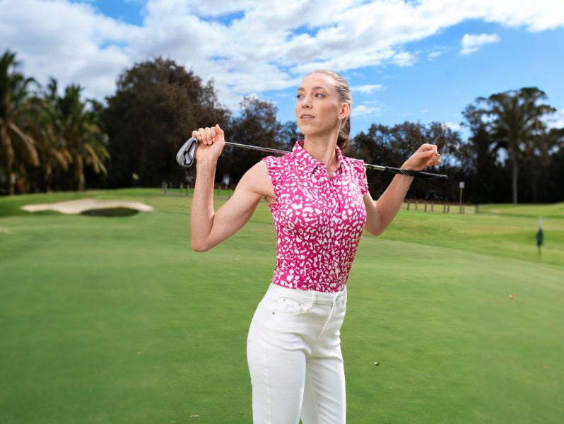Woman wearing pink sleeveless floral golf shirt playing golf on golf course