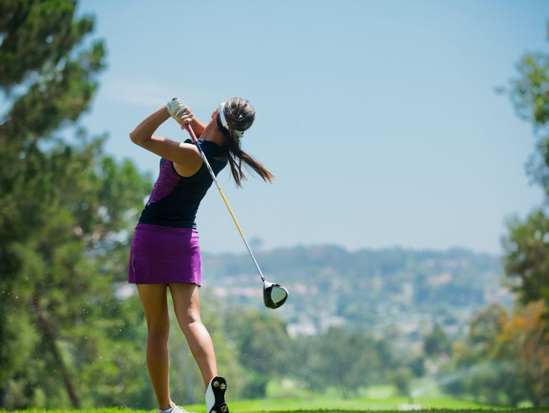 Lady finishes golf shot