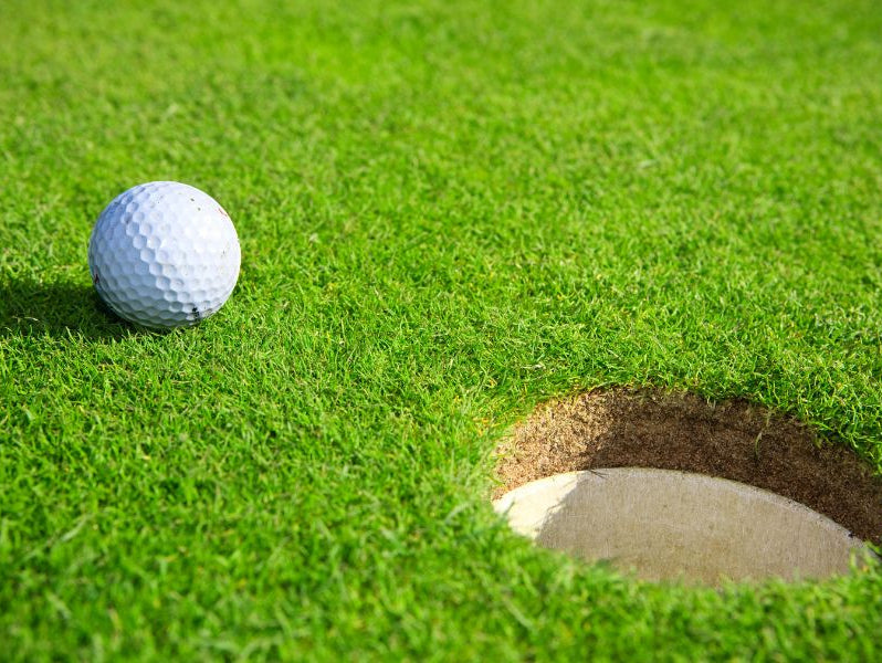 There is a golf ball next to the golf hole
