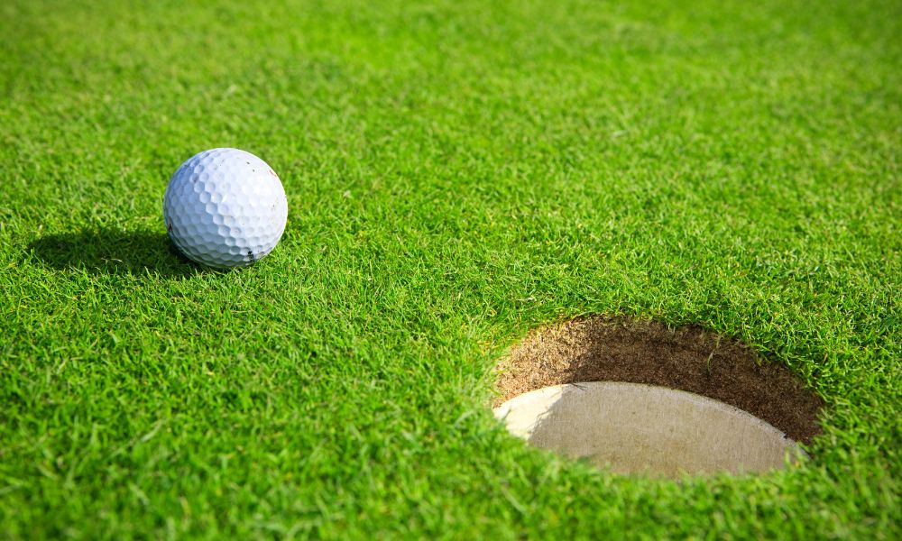 There is a golf ball next to the golf hole